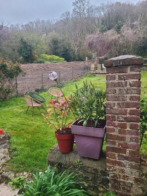 A garden with potted plants, a brick wall, and a wooden fence. - Large sea view house near beach & boating (Honfleur)