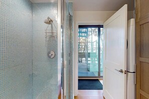 A bathroom with a glass shower enclosure, a white door, and a view of an outdoor deck. - Contemporary 2BR Lakefront Finger Lakes (Dundee)