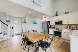 A modern kitchen with white cabinets, stainless steel appliances, and a wooden dining table with chairs. - 1BR - loft withexpansive lake views, deck & grill (Dundee)
