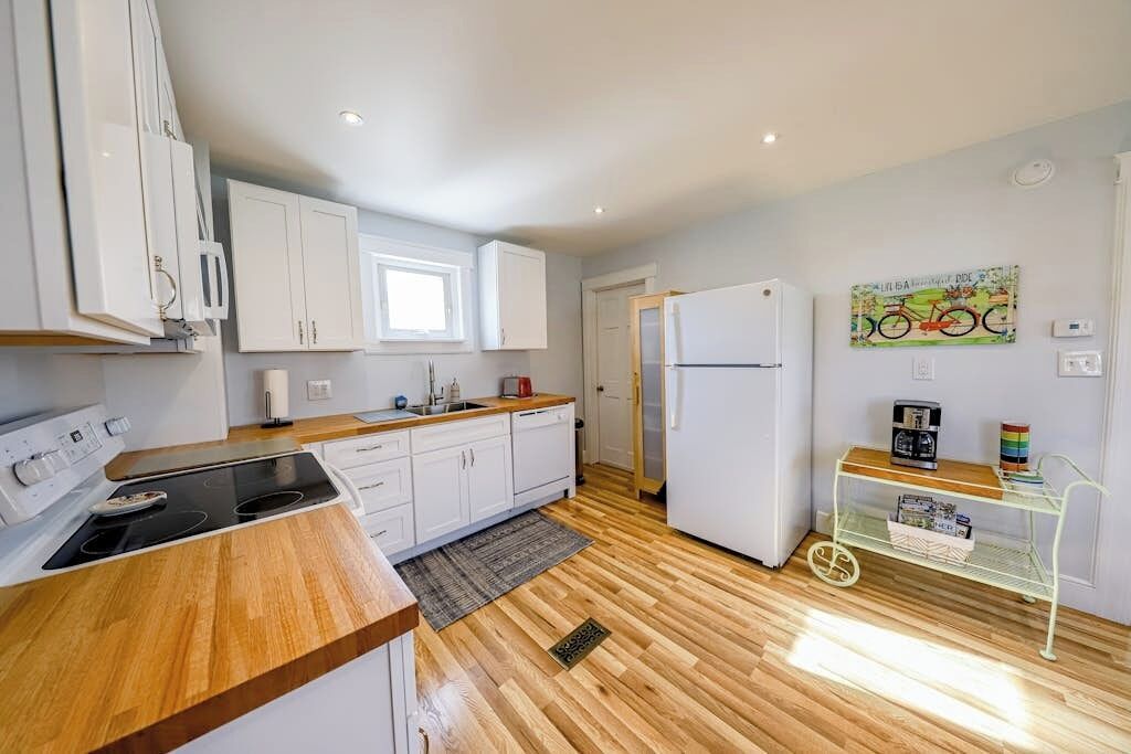 Eine moderne Küche mit weißen Schränken, einer Holzausziehtafel und einem eingebauten Herd.