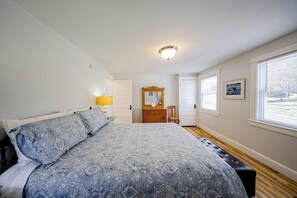 Une chambre à coucher avec un grand lit, une commode, un miroir et une fenêtre.