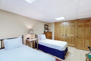 A bedroom with two beds, a wooden wardrobe, a desk with a lamp, and a framed picture on the wall. - 3BR Home near lake withmedia room, fireplace, grill (Hague)