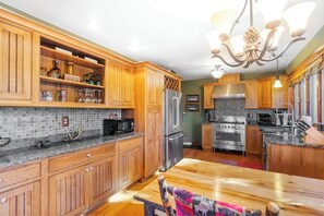 A kitchen with wooden cabinets, a stainless steel refrigerator, a stove, and a chandelier. - Scenic lakefront 4BR with water access & dock (Kattskill Bay)