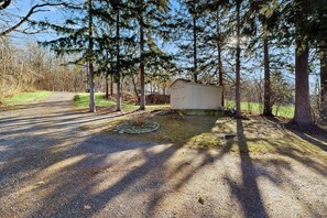 A gravel driveway leading to a small, single-story shed in a wooded area.