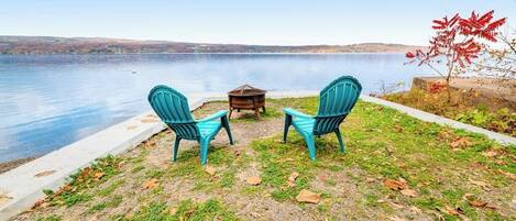 A lakeside seating area with two chairs and a table.