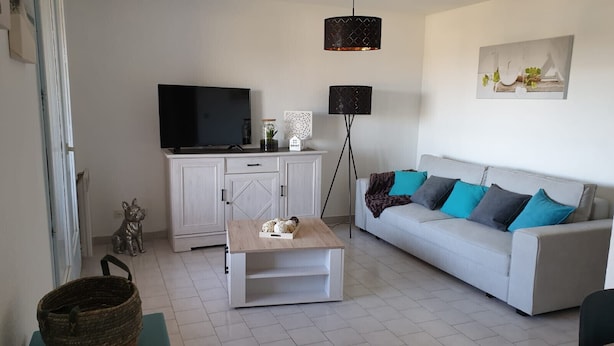 Ein Wohnzimmer mit einer Couch, einem Couchtisch, einem Fernseher und einer Lampe.