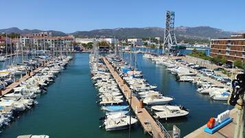 A marina with numerous boats docked, a clear sky, and a mountainous backdrop.