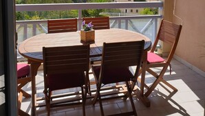Ein Balkon mit Tisch und Stühlen, der einen malerischen Blick auf ein Gewässer und Hügel bietet.