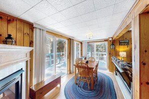 A room with a dining table, chairs, a patterned rug, a bench, and a fireplace. - 3BR dog-friendly cottage with wrap-around deck (Chestertown)