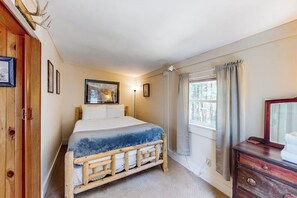 A bedroom with a wooden bed, a dresser, a window with curtains, and framed pictures on the wall. - 3BR dog-friendly cottage with wrap-around deck (Chestertown)