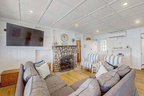 A living room with a stone fireplace, a flat-screen TV mounted on the wall, and striped armchairs. - 2BR lakefront home with grill - great views (Jerusalem)