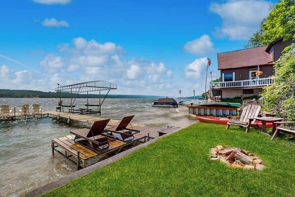 A lakeside property with a dock, lounge chairs, a fire pit, and a building with a balcony. - 2BR lakefront home with grill - great views (Jerusalem)
