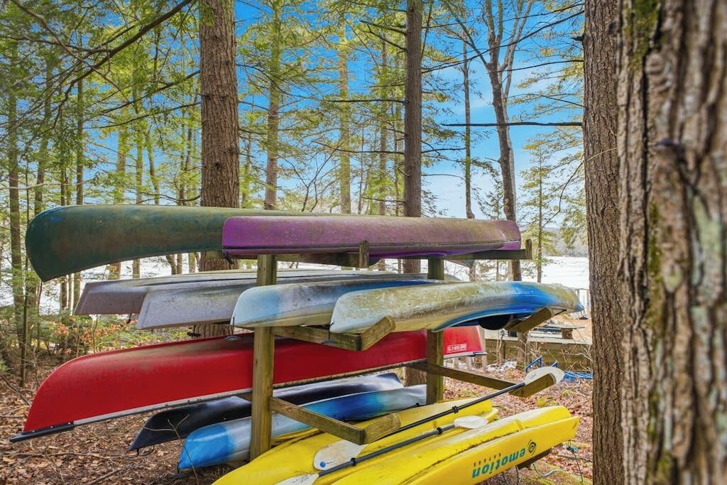 Un rastrillo de madera sostiene varios kayaks de diferentes colores.