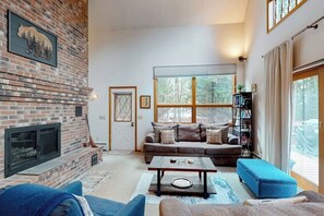 Ein Wohnzimmer mit Kamin aus Backstein, einer Sofagarnitur, einem Couchtisch und einem Bücherregal.