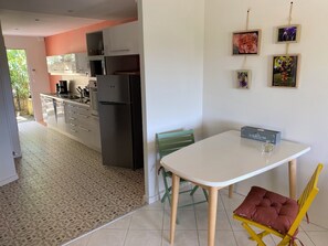 Eine kompakte Küche mit einem Kühlschrank, einem Esstisch mit Stuhl und einer kleinen Schrank.