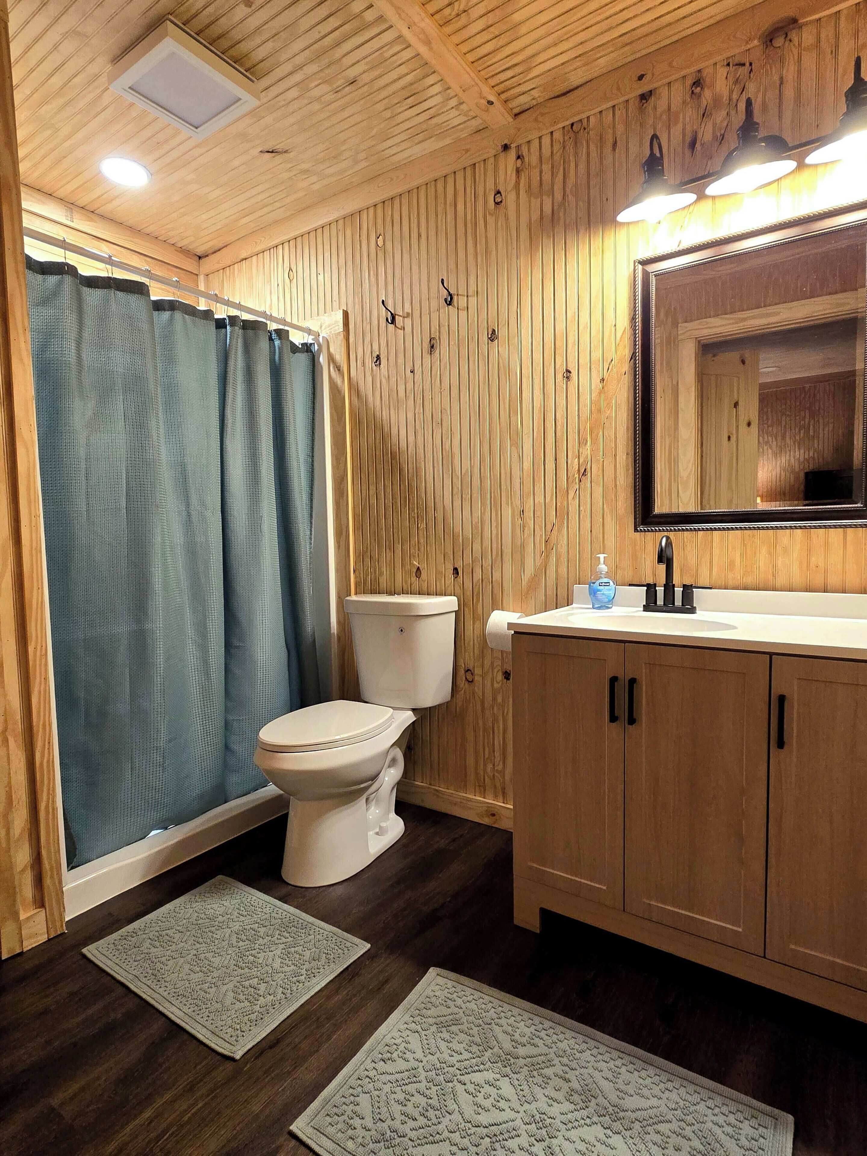 A wooden-paneled bathroom with a toilet, sink, and mirror.