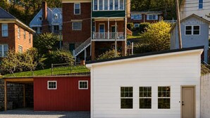 Un barrio residencial con un garaje blanco, un cobertizo rojo y una casa de ladrillo con balcón.