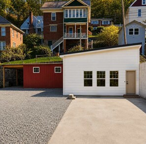 A residential area with a white garage, a red shed, and a brick house with a balcony. - The Lodge at Welch-The Cabin (Welch)