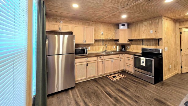 Una cocina moderna con armarios de madera, electrodomésticos de acero inoxidable y suelo de madera.