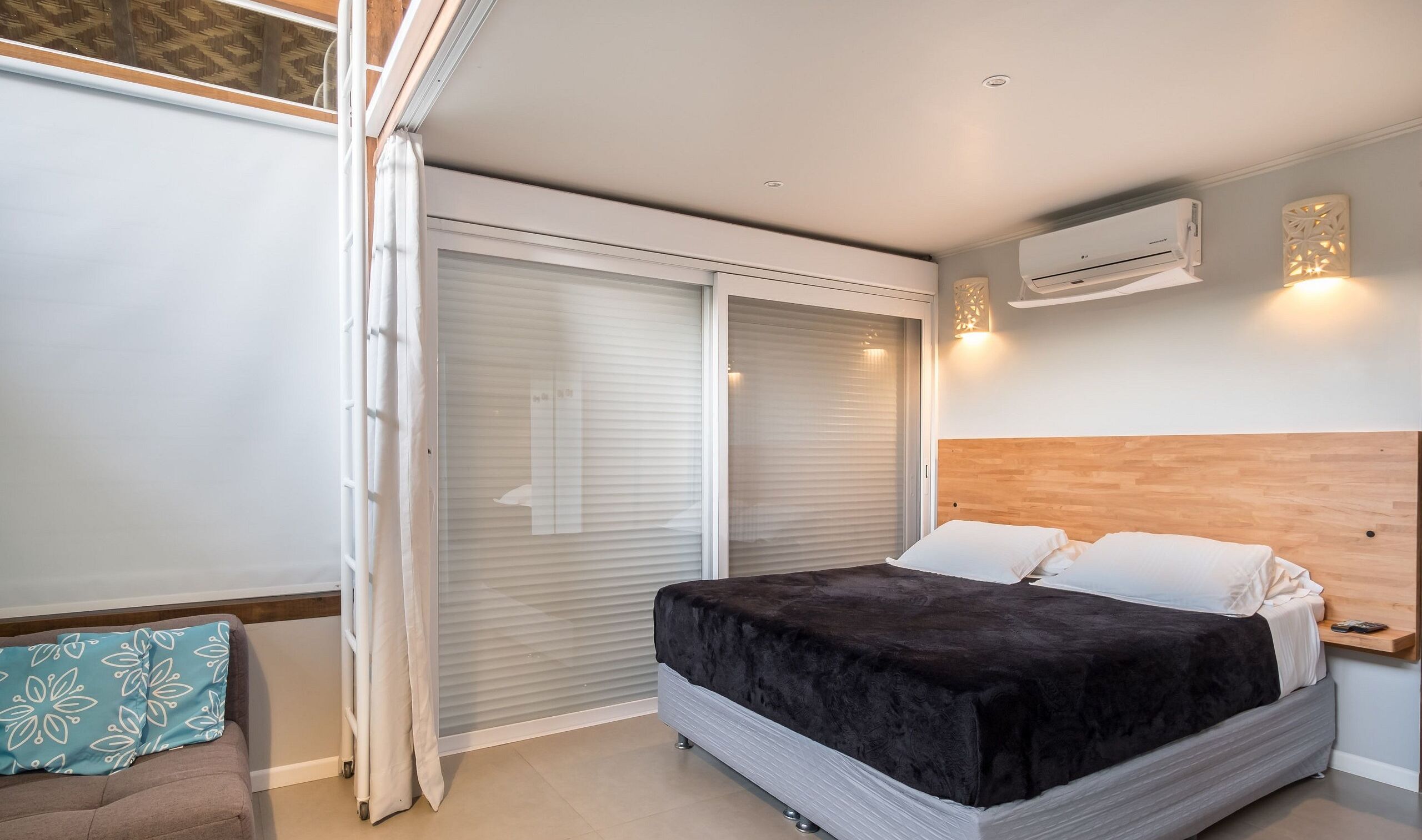 A bedroom with a bed, a sliding door, an air conditioning unit, and a small bedside table.