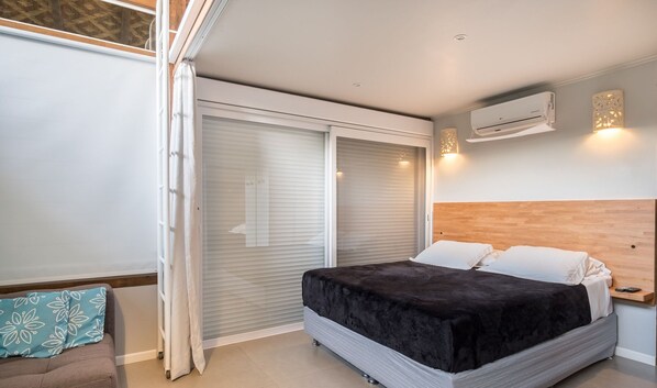Una camera da letto con un letto, una porta scorrevole, un condizionatore d'aria e un piccolo comodino.