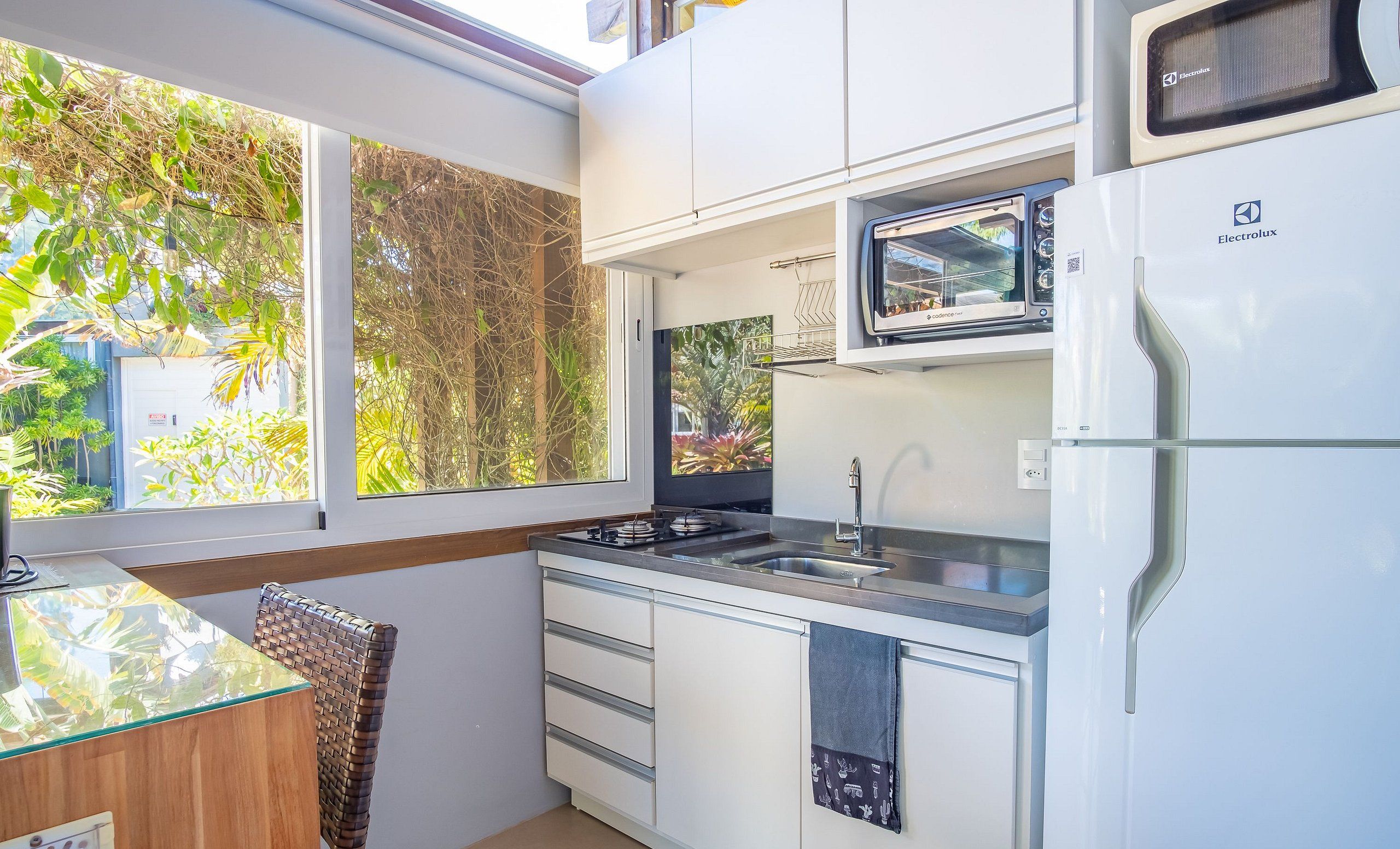 A compact kitchen with a microwave, sink, and a small window overlooking greenery.