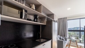 Cozinha moderna com bancada preta, eletrodomésticos de aço inoxidável e área de jantar com vista.