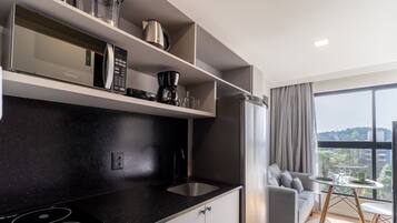 A modern kitchen with a black countertop, stainless steel appliances, and a dining area with a view.