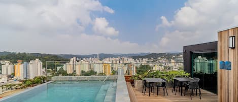 A rooftop pool with a view of a cityscape and mountains.