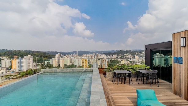 Piscina no terraço com vista para a paisagem urbana e montanhas.