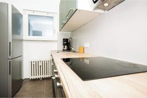 A compact kitchen with a built-in stove, a coffee maker, and a window above the counter. - Penthouse Wohnung mit Balkon (Würzburg)