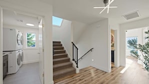 Ein modernes Interieur mit einer Treppe, einer Waschgelegenheit und Blick durch eine offene Tür.