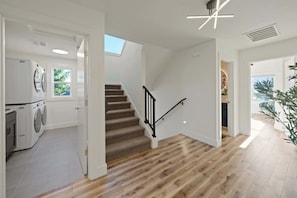 A modern interior with a staircase, a laundry area, and a view through an open door. - Luxury Designer Home -Private Oasis, Jacuzzi, Spa (Newberg)