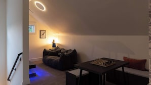 Ein gemütliches Wohnzimmer mit einer Couch, einem Tisch mit einem Schachspiel und einer Lampe.