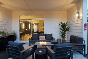 An outdoor seating area with a fire feature, a dining area visible through a glass door, and a fire extinguisher mounted on the wall.