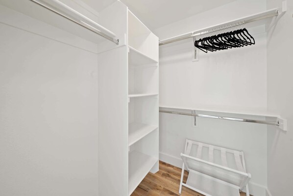 A white closet with open shelves and a hanging rack.