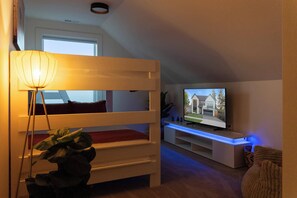 A room with a bunk bed, a television on a stand, and a plant.