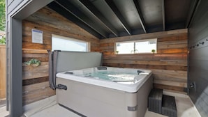 Ein Whirlpool in einer Holzhütte mit Fenster und einem Schild zu den Sicherheitsregeln für den Whirlpool.