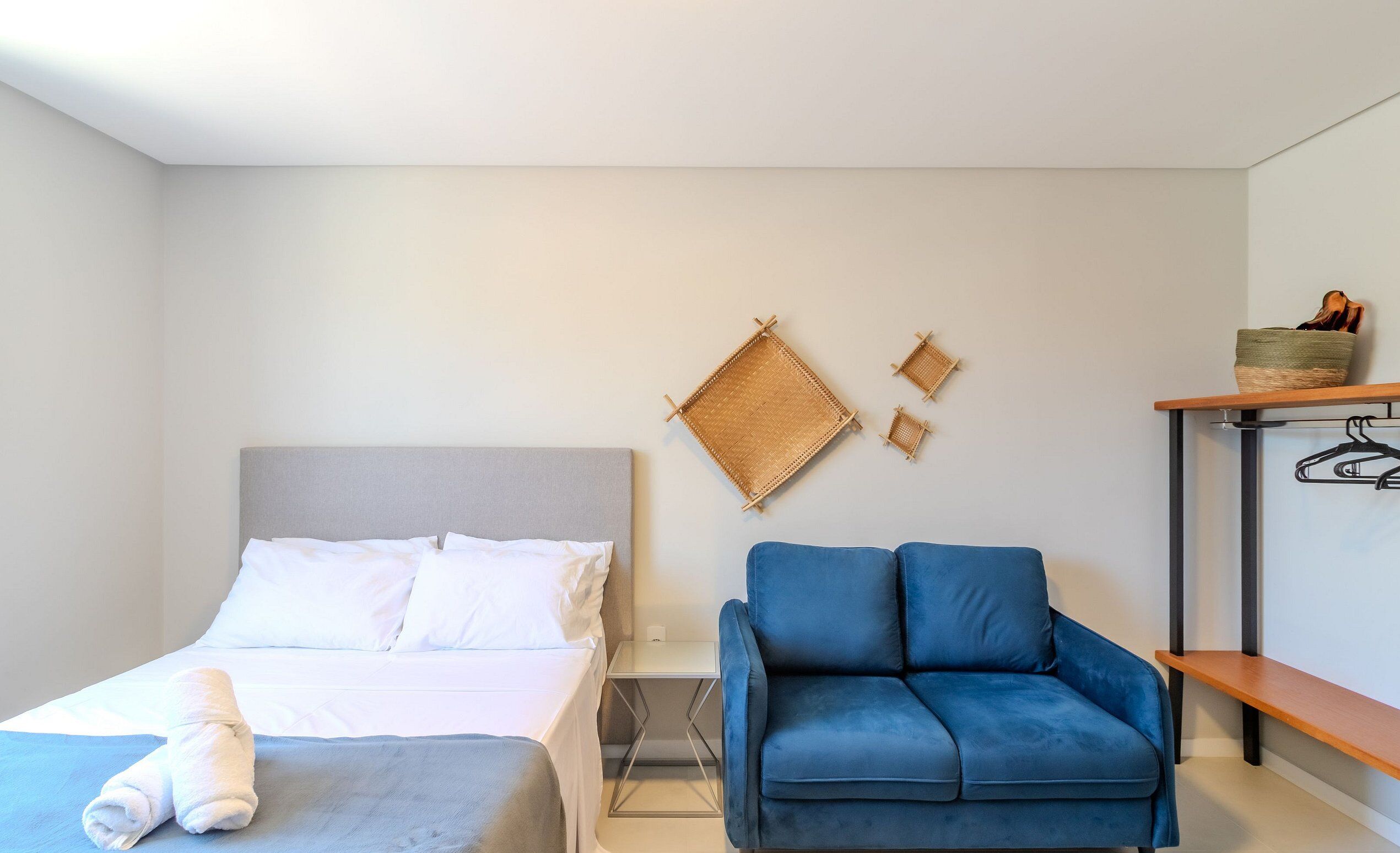 Ein Hotelzimmer mit einem Bett, einem blauen Sofa, einem Wandregal und einem kleinen Tisch.