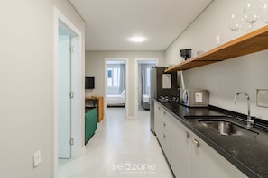 A modern kitchen with a black countertop, stainless steel sink, and a wooden shelf above the sink. - 2BR w/ Self Check-in 600m Beach BC Dpr0007 (Balneário Camboriú)