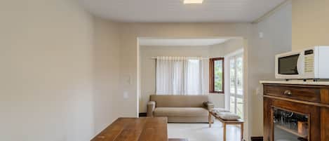 A living room with a wooden table, a sofa, a television, and a cabinet with glass doors.