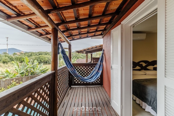 A wooden balcony with a hammock, a bed with a headboard, and a view of greenery. - 2BR Duplex w/ Pool 350m From Sea Vle003 (Bombinhas)