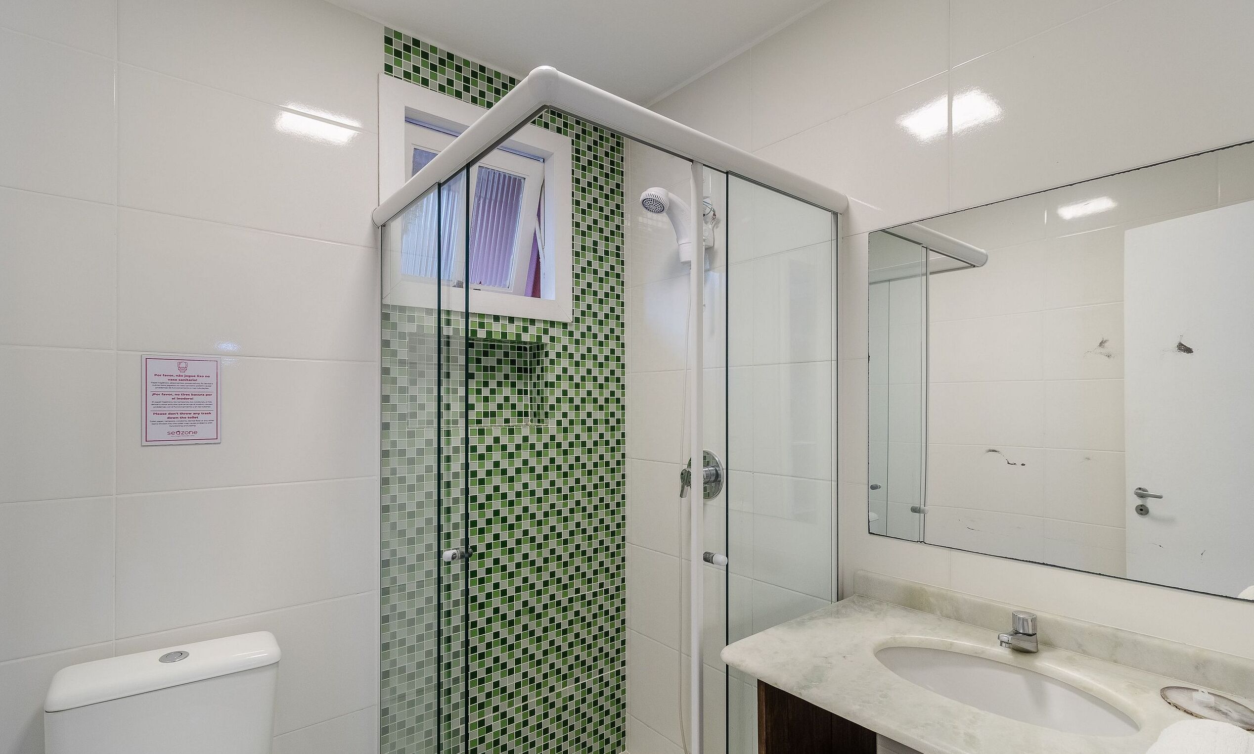 Ein Badezimmer mit Dusche, Toilette, Waschbecken und Spiegel.