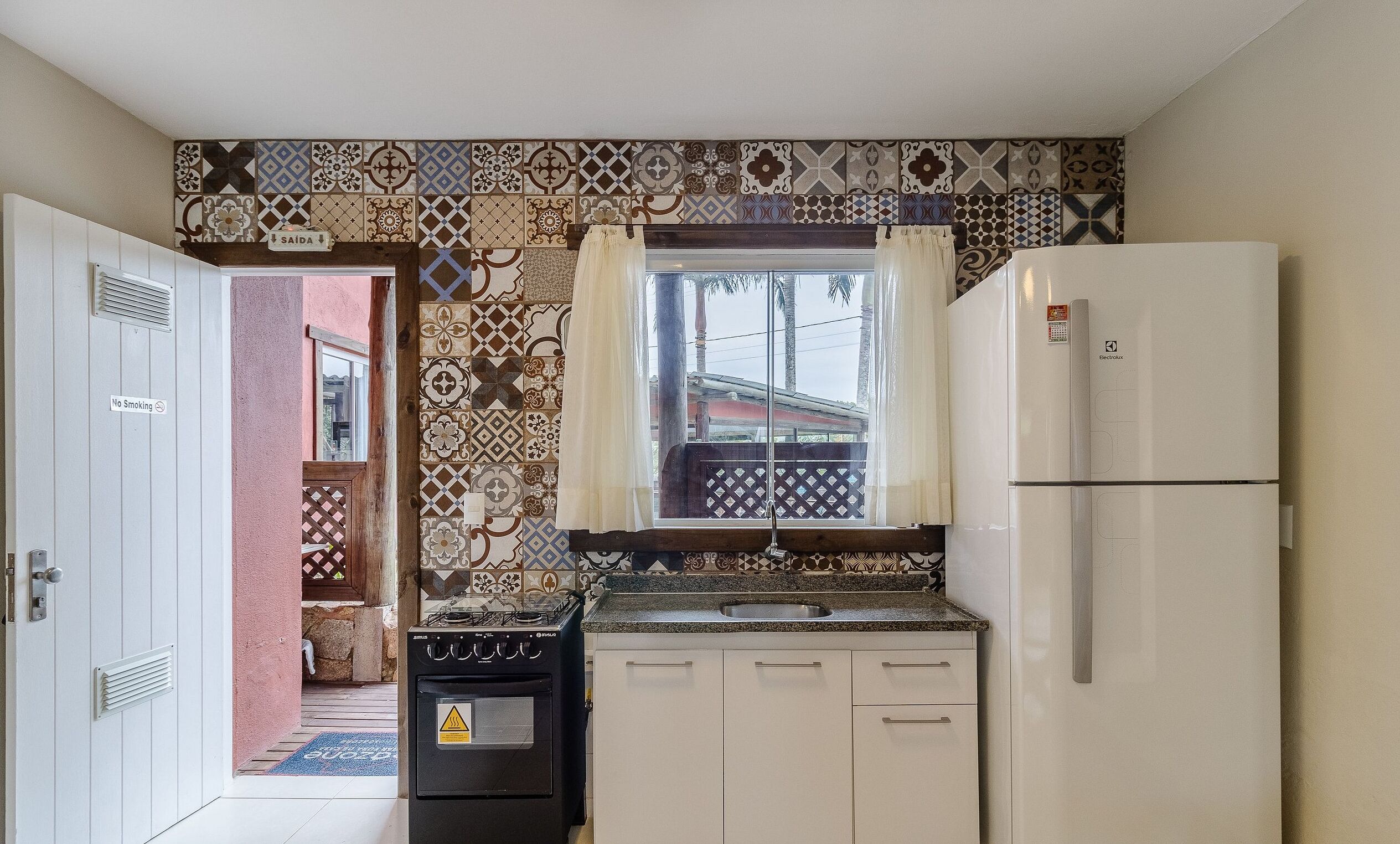 A compact kitchen with a gas stove, a sink, and a white refrigerator.