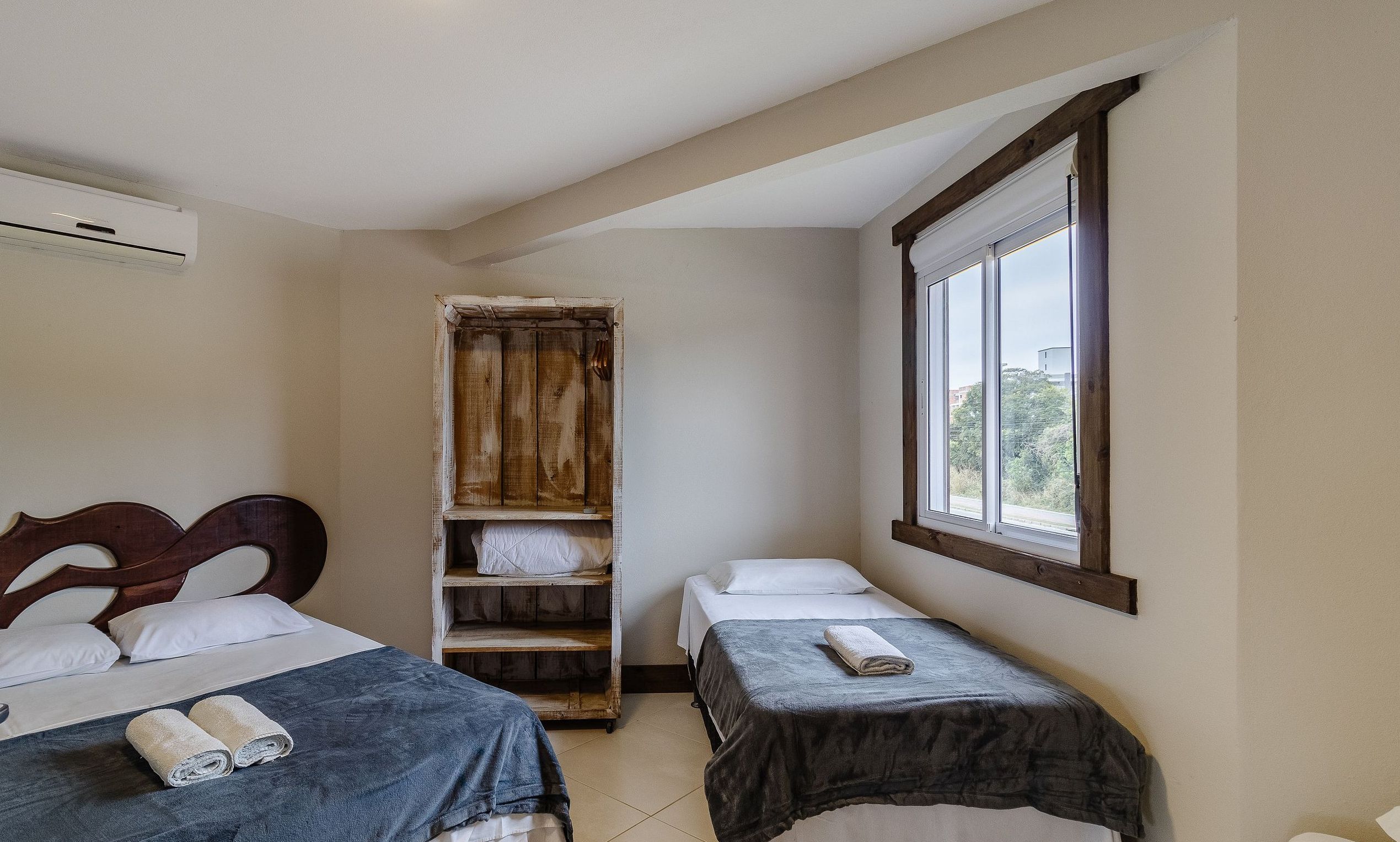 Ein Schlafzimmer mit zwei Betten, einem Holzschrank und einem Fenster.