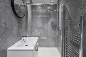 Une salle de bain moderne avec une douche à parois de verre, un lavabo blanc et un porte-serviettes.