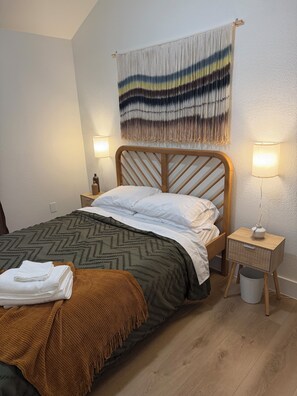 A neatly made bed with a wooden headboard, a bedside table with a lamp, and a wall hanging above. - Cozy Modern 3-bedroom house with AC in tranquil Fort Worth (Fort Worth)