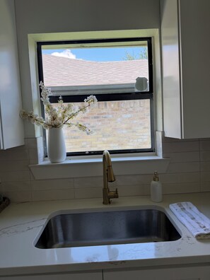 Eine Küche mit Fenster, Spüle und einer Vase mit Blumen.