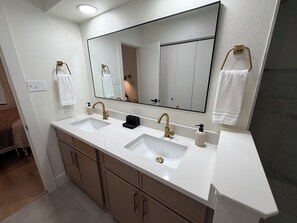 A bathroom with two sinks, a large mirror, and a towel rack. - Cozy Modern 3-bedroom house with AC in tranquil Fort Worth (Fort Worth)