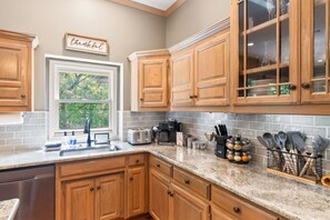 A kitchen with wooden cabinets, a window, and a countertop with various kitchen items.